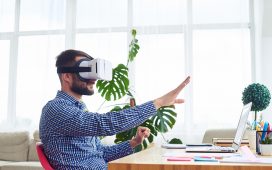 Man with VR headset sitting at a desk