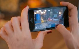 Woman using smartphone with augmented reality app and placing furniture in room