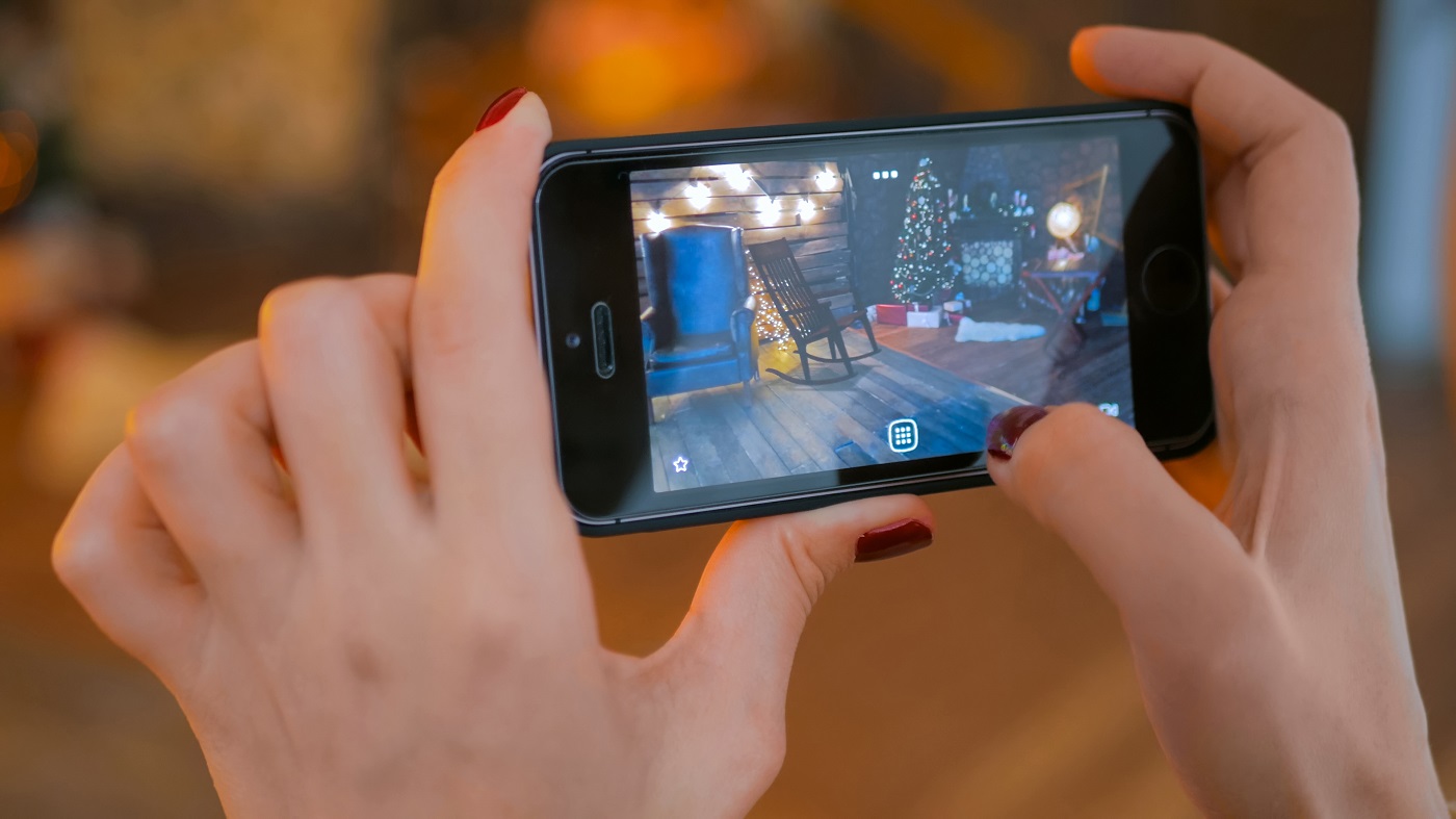 Woman using smartphone with augmented reality app and placing furniture in room