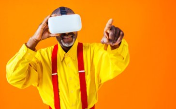 Cool senior man with fashionable clothing using a VR headset